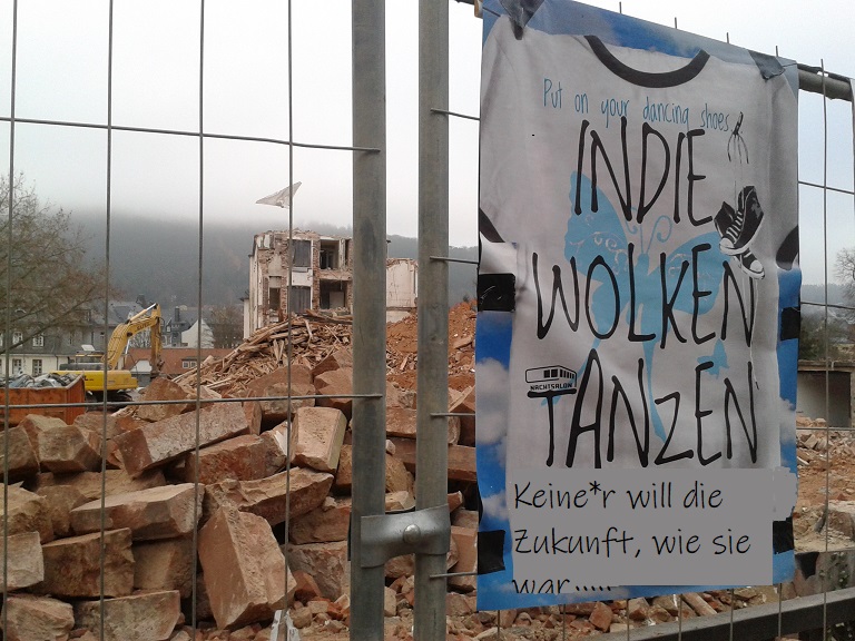 Baugerüst mit einem beschrifteten Plakat: In die Wolken tanzen. Bild: Nachtsalon Marburg